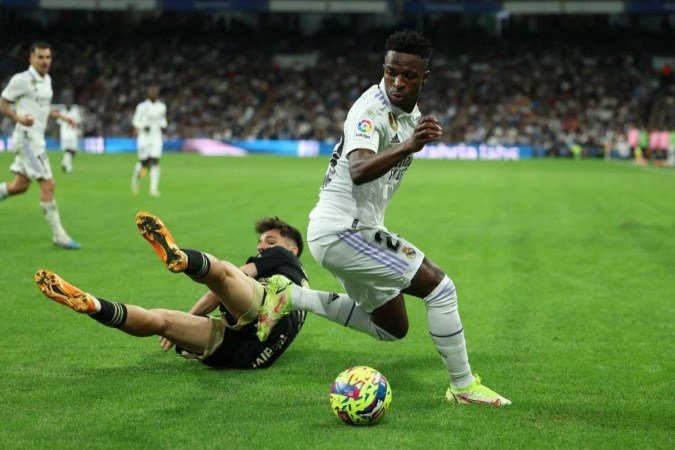 O atacante brasileiro do Real Madrid, Vinicius Junior (R), disputa com o meio-campista espanhol do Celta de Vigo, Gabriel Veiga, durante a partida de futebol da liga espanhola entre o Real Madrid CF e o RC Celta de Vigo no estádio Santiago Bernabéu, em Madri