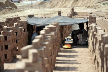 Trabalhadores paquistaneses de uma olaria descansam sob um pedaço de tecido durante a onda de calor, -  (crédito:  AFP)