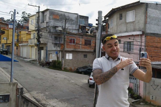 O influenciador Murilo Duarte transmite um vídeo ao vivo na favela Jardim João XXIII em São Paulo, Brasil. (19/04/2023) - (crédito: Miguel SCHINCARIOL/AFP) O influenciador Murilo Duarte transmite um vídeo ao vivo na favela Jardim João XXIII em São Paulo, Brasil. (19/04/2023) - (crédito: Miguel SCHINCARIOL/AFP)