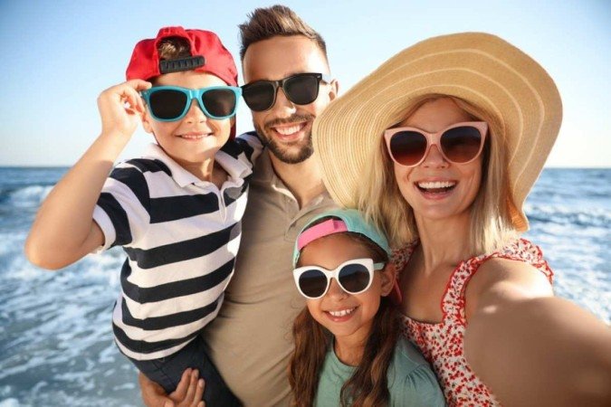 Família feliz tirando selfie na praia perto do mar -  (crédito:  Getty Images/iStockphoto)