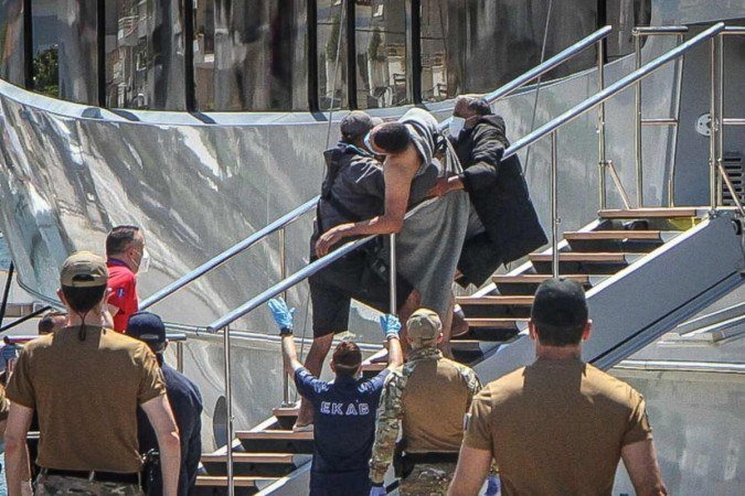 Sobrevivente é carregado por bombeiros, no porto da cidade grega de Kalamata: suspeitas de que atravessadores trancaram centenas no porão -  (crédito: Eurokinissi/AFP)