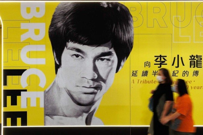 In this photo taken on July 15, 2023 visitors walk past a poster for the Bruce Lee exhibition at the Hong Kong Heritage Museum in Hong Kong, ahead of the 50th anniversary of the martial arts star's death on July 20. The martial arts legend Bruce Lee, whose films spawned a kung fu craze around the world, was one of the first Asian men to achieve Hollywood superstardom, and his influence can still be felt in Hong Kong as fans held exhibitions and martial arts workshops this week to mark the 50th anniversary of his death.