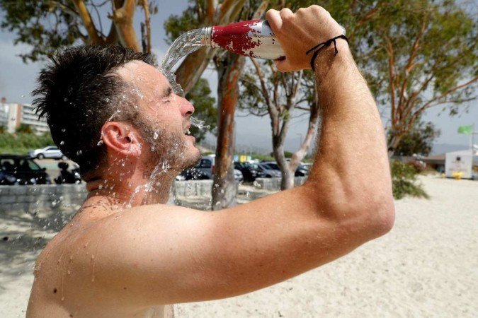 Banhista joga água no rosto para se refrescar na praia de Ricanto, em Ajaccio, na ilha sa da Córsega, em 19 de julho de 2023. Europa vem sendo atingida por uma grande onda de calor. - (crédito: Pascal Pochard-Casabianca/AFP) Banhista joga água no rosto para se refrescar na praia de Ricanto, em Ajaccio, na ilha sa da Córsega, em 19 de julho de 2023. Europa vem sendo atingida por uma grande onda de calor. - (crédito: Pascal Pochard-Casabianca/AFP)