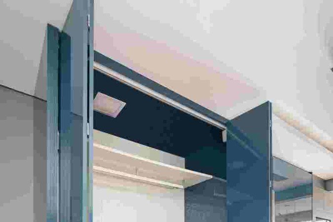 Área de serviços oculta por marcenaria azul, criada pelo escritório Spaço Interior