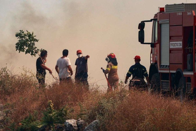 Bombeiros e civis enfrentam uma parede de fumaça enquanto os incêndios florestais queimam, na parte norte da ilha grega de Corfu em 24 de julho de 2023. - (crédito: Reprodução/ Konontarinis GIORG / EUROKINISSI / AFP) Bombeiros e civis enfrentam uma parede de fumaça enquanto os incêndios florestais queimam, na parte norte da ilha grega de Corfu em 24 de julho de 2023. - (crédito: Reprodução/ Konontarinis GIORG / EUROKINISSI / AFP)