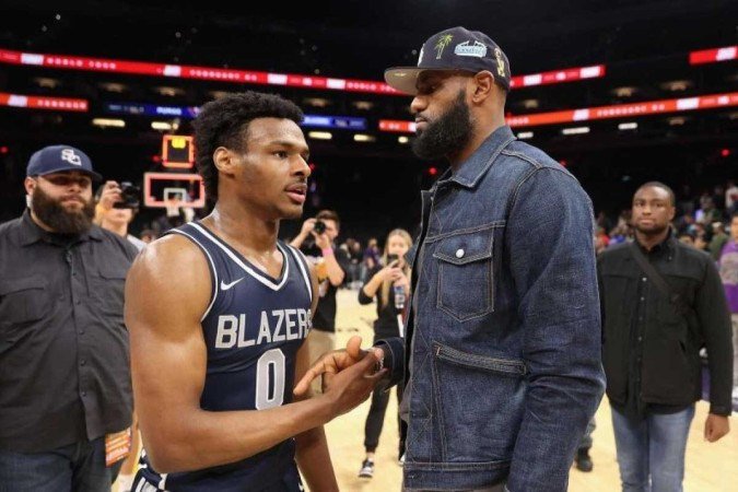 (FILES) In this file photo taken on December 11, 2021 Bronny James #0 of the Sierra Canyon Trailblazers is greeted by his father and NBA player LeBron James after defeating the the Perry Pumas in the Hoophall West tournament at Footprint Center in Phoenix, Arizona. LeBron James has agreed to on a two-year NBA contract extension with the Los Angeles Lakers worth $97.1 million, according to multiple reports on Wednesday. - (crédito: Christian Petersen/AFP) (FILES) In this file photo taken on December 11, 2021 Bronny James #0 of the Sierra Canyon Trailblazers is greeted by his father and NBA player LeBron James after defeating the the Perry Pumas in the Hoophall West tournament at Footprint Center in Phoenix, Arizona. LeBron James has agreed to on a two-year NBA contract extension with the Los Angeles Lakers worth $97.1 million, according to multiple reports on Wednesday. - (crédito: Christian Petersen/AFP)