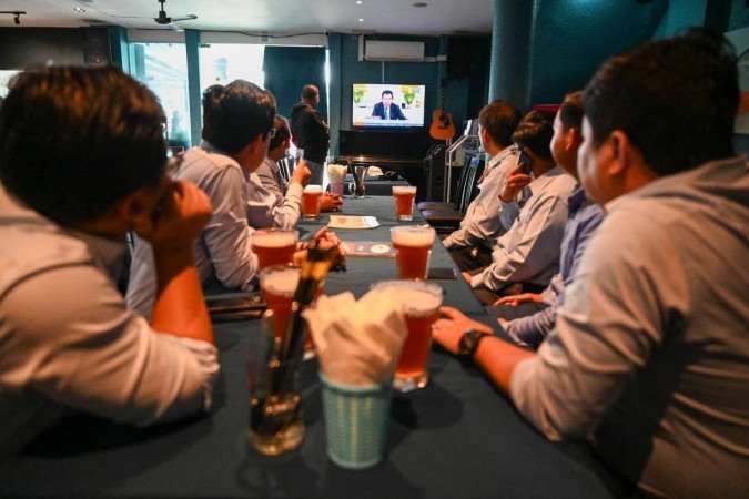 As pessoas assistem enquanto o primeiro-ministro do Camboja, Hun Sen, fala durante uma declaração especial na televisão em um restaurante em Phnom Penh em 26 de julho de 2023.
- (crédito: Reprodução/ TANG CHHIN Sothy / AFP) As pessoas assistem enquanto o primeiro-ministro do Camboja, Hun Sen, fala durante uma declaração especial na televisão em um restaurante em Phnom Penh em 26 de julho de 2023.
- (crédito: Reprodução/ TANG CHHIN Sothy / AFP)