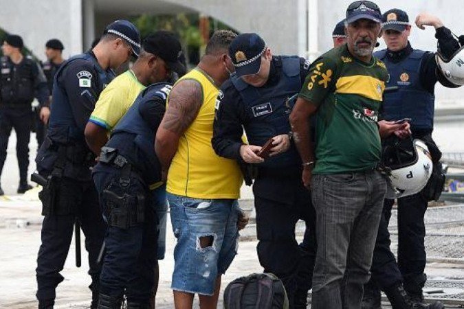 Homens são detidos perto do Palácio do Planalto em 8 de janeiro; segundo o STF, das 2.151 pessoas presas em flagrante em janeiro, apenas 251 permanecem detidas em regime fechado -  (crédito: Ton Molina/AFP)