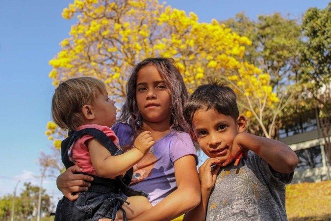   04/08/2023 Crédito: Kayo Magalhães/CB/D.A Press. Brasil. Brasilia - DF. Cidades. Ipê amarelo colore Brasília. Na foto, Yasmin (1), Alice (7), John (4).