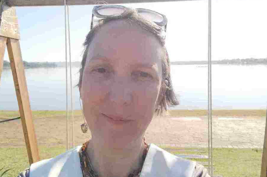 Mulher branca de cabelo amarrado olhando para frente de óculos na cabeça