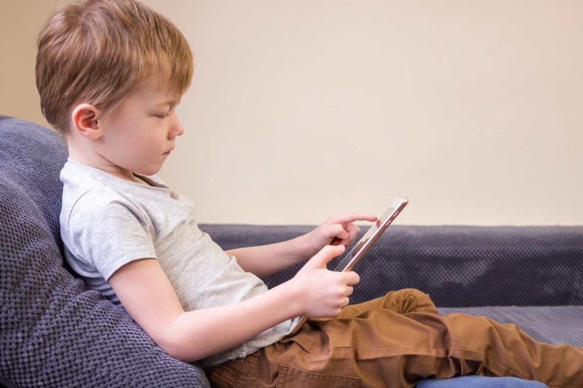 Duas Meninas No Sofá à Noite Com Um Tablet Digital. Jogos Online