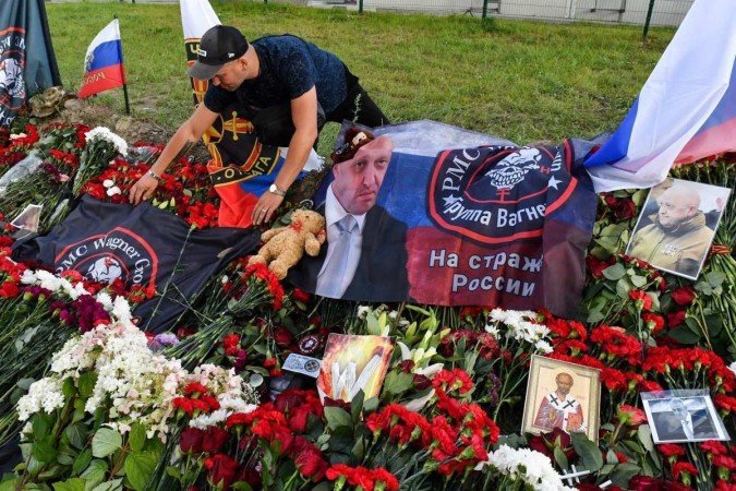 Homem arruma uma bandeira com o logotipo do grupo Wagner em um memorial improvisado para Yevgeny Prigozhin, em São Petersburgo - (crédito: AFP) Homem arruma uma bandeira com o logotipo do grupo Wagner em um memorial improvisado para Yevgeny Prigozhin, em São Petersburgo - (crédito: AFP)