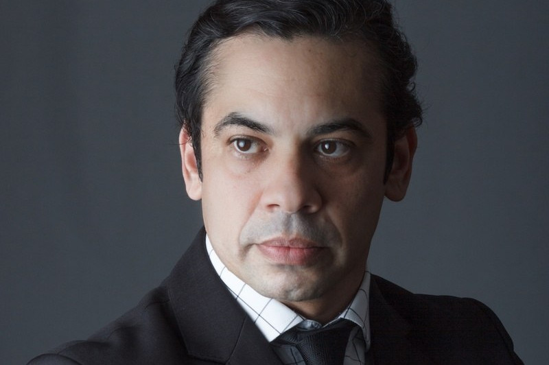 Homem branco de terno com bra&ccedil;os cruzados.