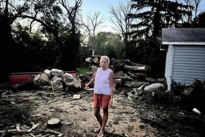 Mary Anne Yackel diante do local onde viu Danilo ser escoltado pela polícia, saindo da mata (ao fundo)