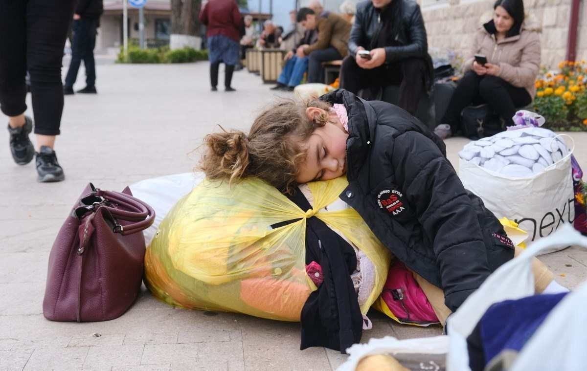 Menina dorme em rua de Stepanakert, enquanto aguarda, com a família, o transporte para fugir da capital 