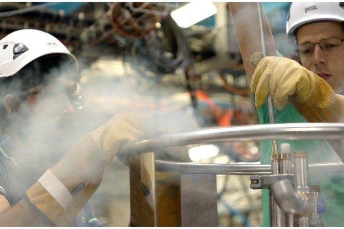 Engenheiros adicionam hélio líquido ao sistema para manter a antimatéria a -270°C, perto da temperatura mais baixa possível, o zero absoluto - (crédito: BBC) Engenheiros adicionam hélio líquido ao sistema para manter a antimatéria a -270°C, perto da temperatura mais baixa possível, o zero absoluto - (crédito: BBC)
