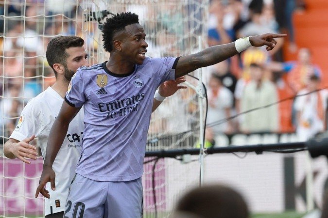 Real Madrid's Brazilian forward Vinicius Junior reacts to being insulted pointing at the stands during the Spanish league football match between Valencia CF and Real Madrid CF at the Mestalla stadium in Valencia on May 21, 2023. (Photo by JOSE JORDAN / AFP) (Photo by JOSE JORDAN/AFP via Getty Images)
- (crédito: JOSE JORDAN/AFP via Getty Images) Real Madrid's Brazilian forward Vinicius Junior reacts to being insulted pointing at the stands during the Spanish league football match between Valencia CF and Real Madrid CF at the Mestalla stadium in Valencia on May 21, 2023. (Photo by JOSE JORDAN / AFP) (Photo by JOSE JORDAN/AFP via Getty Images)
- (crédito: JOSE JORDAN/AFP via Getty Images)