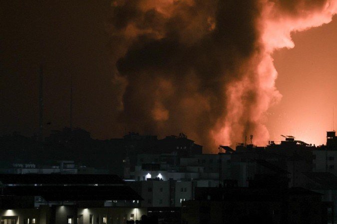 Fogo e fumaça sobem acima de um edifício durante um ataque aéreo israelense na cidade de Gaza, lançado após o ataque do Hamas, que já deixou 600 israelenses mortos -  (crédito: MAHMUD HAMS/AFP)