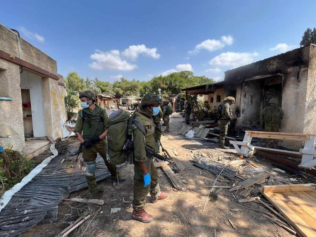 No mesmo kibbutz, soldados das Forças de Defesa de Israel observam a destruição causada pelos assassinos 