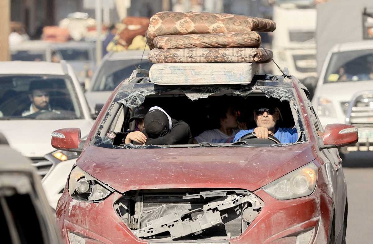 Viajando em um veículo danificado, uma família palestina foge com centenas de outras pessoas após o alerta do exército israelense para deixar suas casas e seguir para o sul antes de uma esperada ofensiva terrestre, na Cidade de Gaza, em 13 de outubro de 2023. 