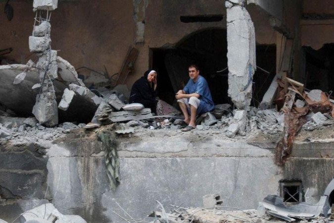 Palestinos sentam-se entre os escombros de um prédio residencial danificado, após ataques israelenses, na Cidade de Gaza - (crédito: Reuters) Palestinos sentam-se entre os escombros de um prédio residencial danificado, após ataques israelenses, na Cidade de Gaza - (crédito: Reuters)