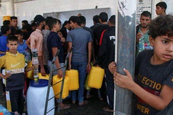 Palestinos recolhem água em uma das poucas estações de abastecimento em Khan Younis - (crédito: Getty Images) Palestinos recolhem água em uma das poucas estações de abastecimento em Khan Younis - (crédito: Getty Images)