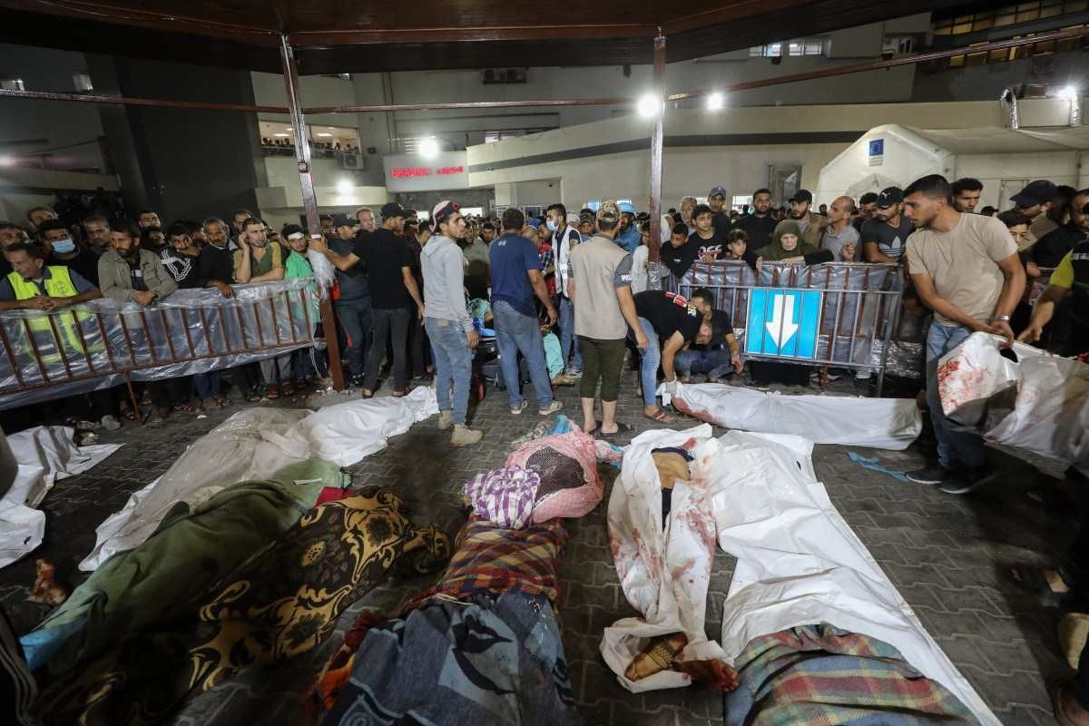 Pessoas se reúnem em torno de corpos de palestinos mortos em ataques aéreos israelenses no hospital Ahli Arab, no centro de Gaza, depois de serem transportados para o hospital Al-Shifa, em 17 de outubro de 2023.       