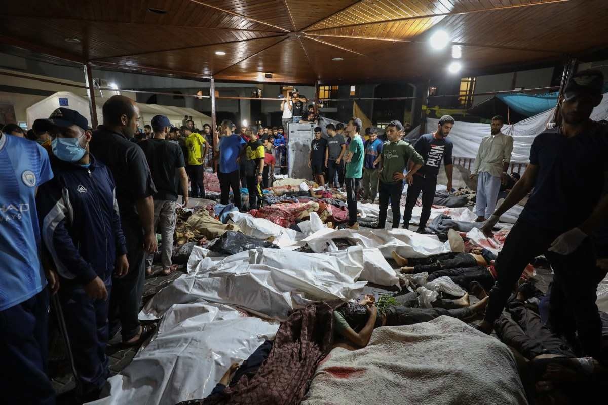 Pessoas se reúnem em torno de corpos de palestinos mortos em ataques aéreos israelenses no hospital Ahli Arab, no centro de Gaza, depois de serem transportados para o hospital Al-Shifa, em 17 de outubro de 2023.       