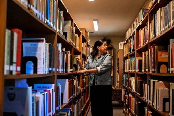 A neta de Mollie Burkhart, Margie Burkhart, folheia livros na biblioteca White Hair Memorial em Hominy