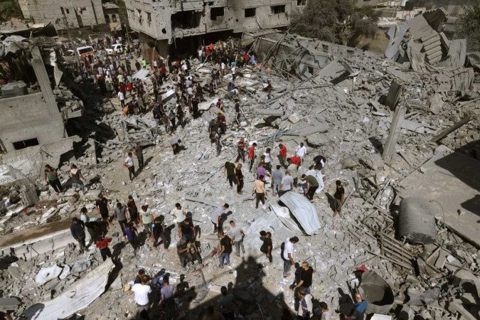 Visão geral dos edifícios destruídos enquanto as pessoas se reúnem em busca de vítimas após um ataque aéreo israelense em Rafah, no sul da Faixa de Gaza, em 17 de outubro de 2023 - (crédito: MOHAMMED ABED / AFP) Visão geral dos edifícios destruídos enquanto as pessoas se reúnem em busca de vítimas após um ataque aéreo israelense em Rafah, no sul da Faixa de Gaza, em 17 de outubro de 2023 - (crédito: MOHAMMED ABED / AFP)