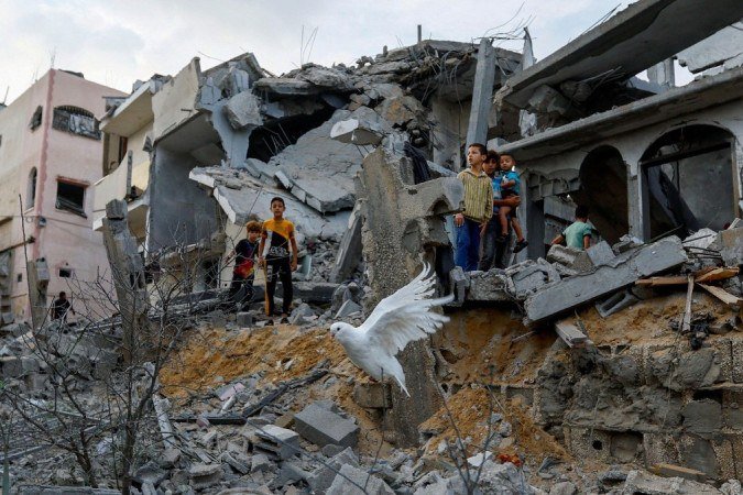 Uma pomba voa sobre os escombros de casas em Khan Younis, no sul da Faixa de Gaza - (crédito: Reuters) Uma pomba voa sobre os escombros de casas em Khan Younis, no sul da Faixa de Gaza - (crédito: Reuters)