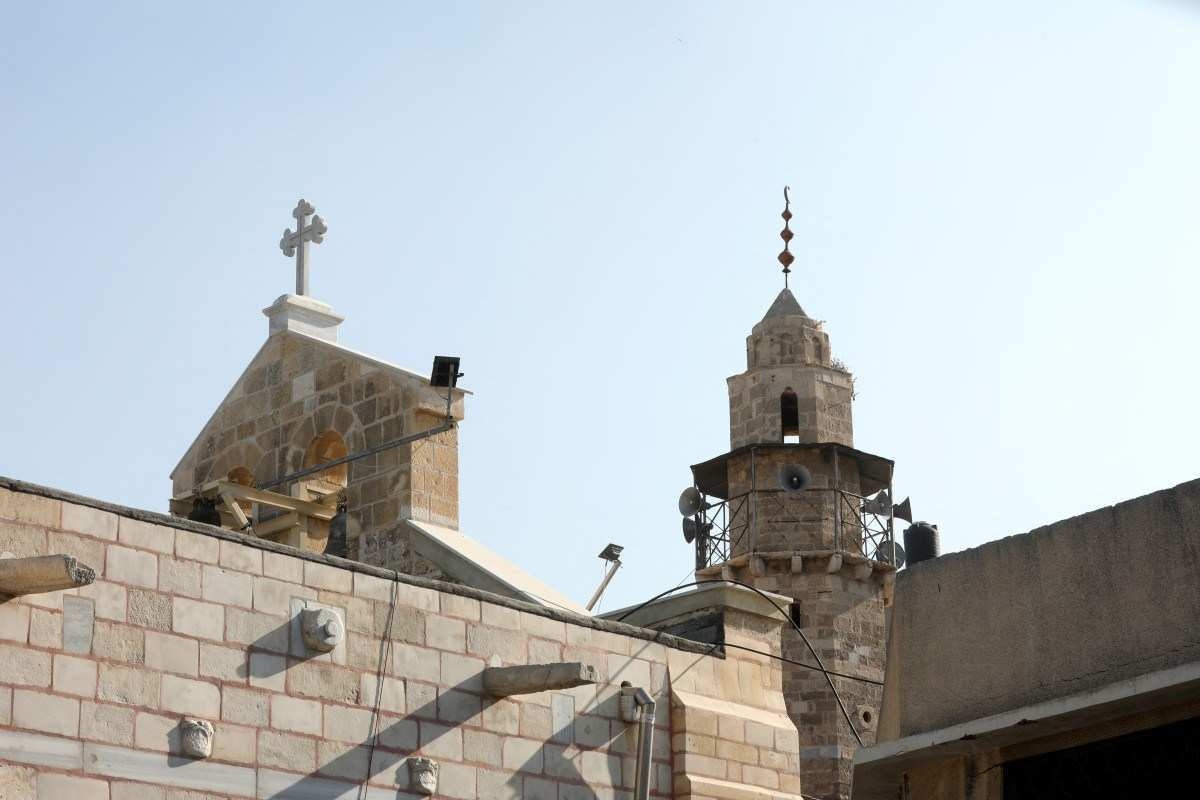 A cruz da Igreja Ortodoxa Grega de Santo Porfírio ao lado do minarete de uma mesquita, um dia depois de a igreja ter sido bombardeada em ataque na Cidade de Gaza, em 20 de outubro de 2023