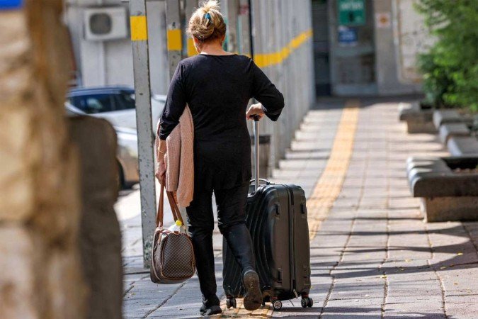 Mulher caminha com bagagem em uma estação rodoviária enquanto se prepara para partir de Kiryat Shmona, no norte de Israel, perto da fronteira com o Líbano, em 19 de outubro de 2023, como parte de uma evacuação na área em meio ao aumento das tensões entre Israel e o movimento xiita libanês Hezbollah - (crédito: Jalaa Marey / AFP) Mulher caminha com bagagem em uma estação rodoviária enquanto se prepara para partir de Kiryat Shmona, no norte de Israel, perto da fronteira com o Líbano, em 19 de outubro de 2023, como parte de uma evacuação na área em meio ao aumento das tensões entre Israel e o movimento xiita libanês Hezbollah - (crédito: Jalaa Marey / AFP)