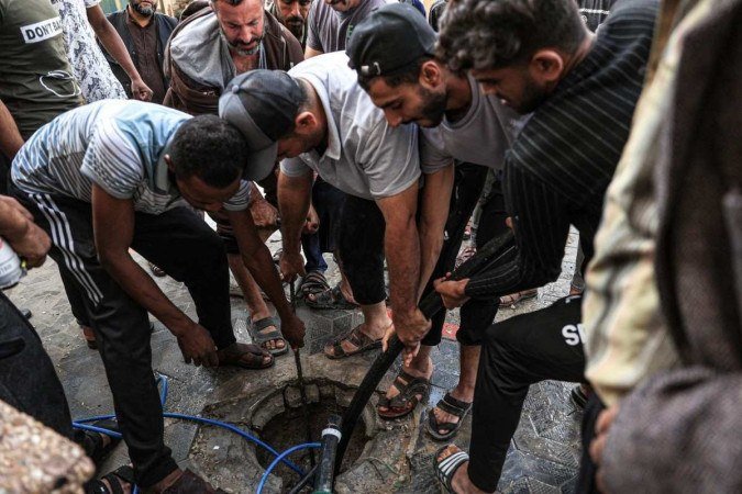 Cidadãos tentam bombear água limpa de um 'poço' na cidade de Rafah, no sul da Faixa de Gaza -  (crédito: SAID KHATIB / AFP)