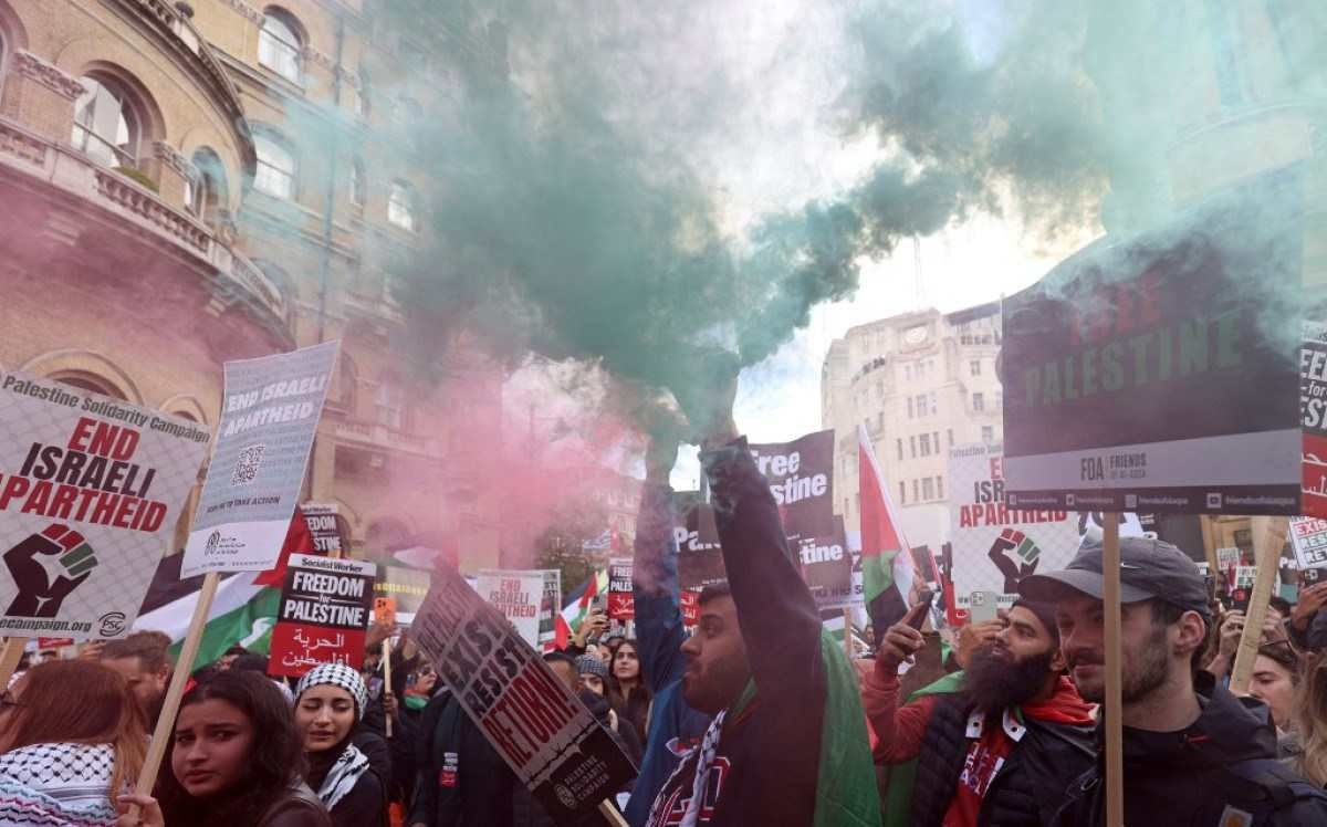 Um manifestante solta uma lata de fumaça enquanto as pessoas se reúnem para participar de uma Marcha pela Palestina, parte de uma manifestação nacional pró-Palestina, em Londres      