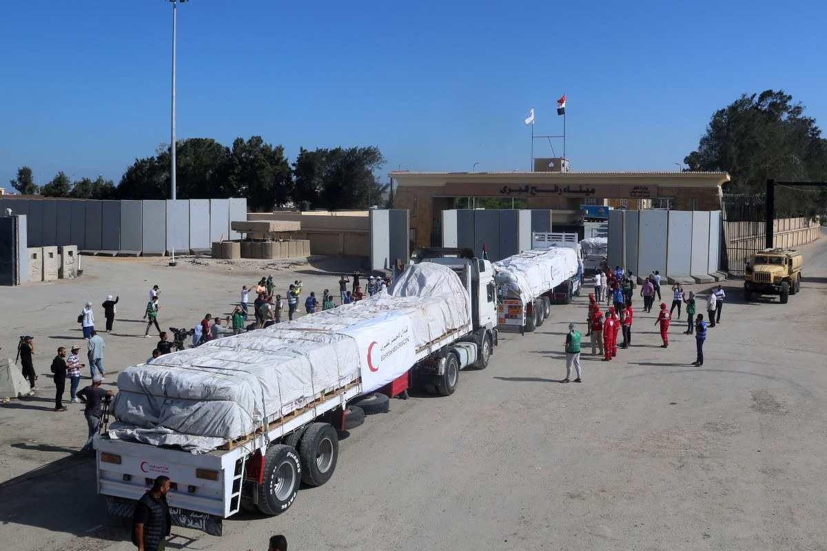 Pessoas no lado egípcio da passagem de fronteira de Rafah observam enquanto um comboio de caminhões transportando ajuda humanitária cruza para a Faixa de Gaza       