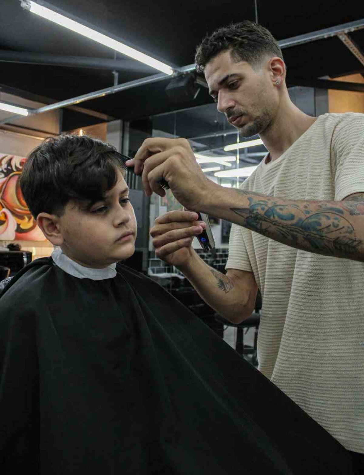 Gabriel Carlos corta o cabelo de João Guilherme, 12: nova geração de profissionais e de consumidores 25/10/2023. Crédito: Kayo Magalhães/CB/D.A Press. Brasil. Brasilia - DF.Cidades. Jovens estão entrando no mercado de trabalho. Na foto, o barbeiro Gabriel Carlos atendendo o João Guilherme Macedo.