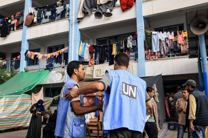 Trabalhadores da Agência das Nações Unidas de Assistência e Obras para os Refugiados da Palestina (UNRWA) conversam no playground de uma escola administrada pela UNRWA que foi convertida em um abrigo para palestinos  -  (crédito: Mahmud HAMS / AFP)