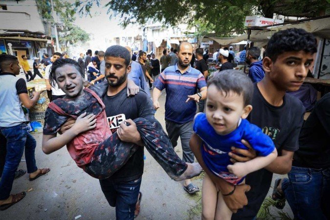 Um homem carrega uma menina ferida após um ataque israelense a um campo de refugiados, no centro da Faixa de Gaza - (crédito: MAHMUD HAMS / AFP) Um homem carrega uma menina ferida após um ataque israelense a um campo de refugiados, no centro da Faixa de Gaza - (crédito: MAHMUD HAMS / AFP)