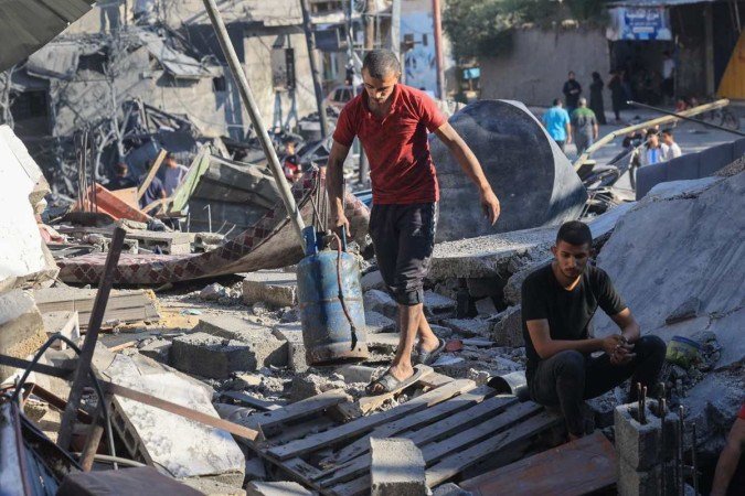 Palestinos revistam os escombros de um prédio desabado após o bombardeio -  (crédito: SAID KHATIB / AFP)