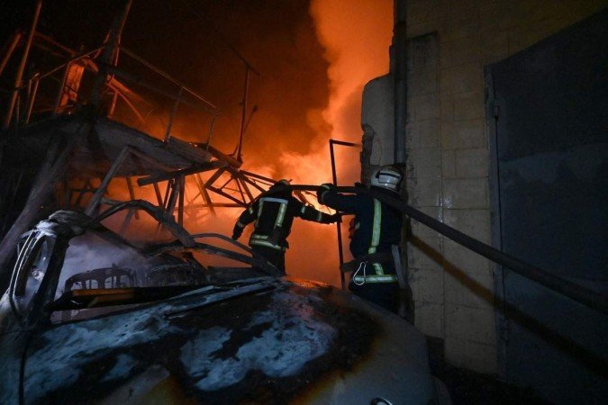 Bombeiros ucranianos trabalham para extinguir um incêndio após um ataque noturno de drones russos em Kharkiv, em 3 de novembro de 2023       -  (crédito: SERGEY BOBOK / AFP)