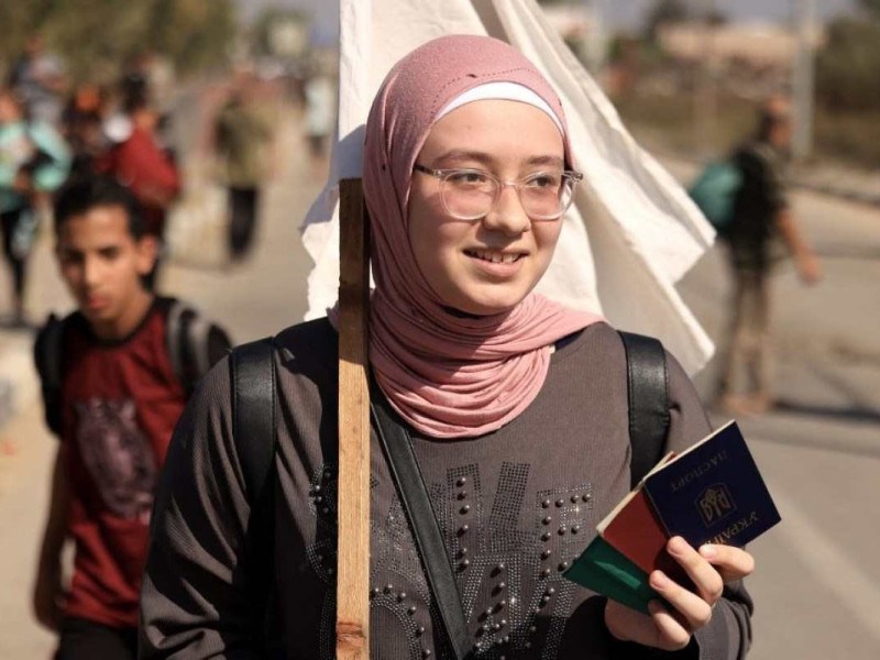 Uma mulher em um hijab está na frente de um tanque.