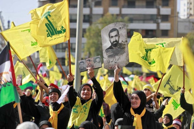 Apoiadores do movimento xiita libanês Hezbollah agitam bandeiras enquanto assistem a um discurso televisionado de seu líder Hassan Nasrallah (invisível) nos subúrbios ao sul da capital libanesa, Beirute, em 3 de novembro de 2023 -  (crédito: Ahmad Al-Rubaye/AFP)