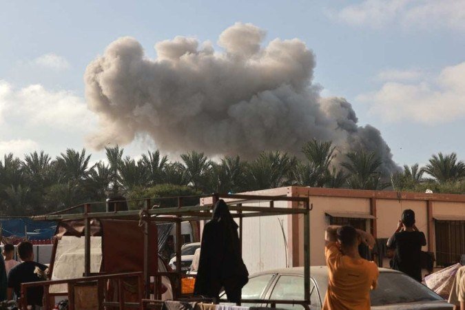 Os palestinos observam uma nuvem de fumaÃ§a apÃ³s o bombardeio israelense em Khan Yunis, no sul da Faixa de Gaza, em 8 de novembro de 2023 -  (crédito: MOHAMMED ABED / AFP)