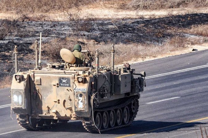 Um veículo blindado do exército israelense se move ao longo de uma estrada em uma posição perto da fronteira com a Faixa de Gaza       -  (crédito: JACK GUEZ / AFP)