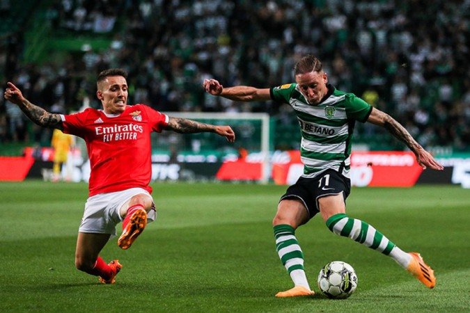Benfica's Spanish midfielder Alex Grimaldo (L) challenges Sporting's Portuguese forward defender Nuno Santos during the Portuguese league football match between Sporting CP and SL Benfica at the Jose Alvalade stadium in Lisbon on May 21, 2023. (Photo by CARLOS COSTA / AFP) (Photo by CARLOS COSTA/AFP via Getty Images)
- (crédito: AFP via Getty Images) Benfica's Spanish midfielder Alex Grimaldo (L) challenges Sporting's Portuguese forward defender Nuno Santos during the Portuguese league football match between Sporting CP and SL Benfica at the Jose Alvalade stadium in Lisbon on May 21, 2023. (Photo by CARLOS COSTA / AFP) (Photo by CARLOS COSTA/AFP via Getty Images)
- (crédito: AFP via Getty Images)