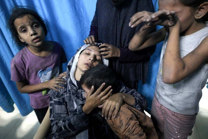 Palestina ferida é confortada pelos filhos, após chegar ao Hospital Nasser, em Khan Younis 
