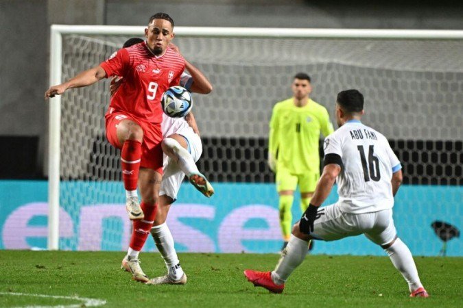 Switzerland's forward #09 Noah Okafor (L) and Israel's midfielder #16 Mohammad Abu Fani vie for the ball during the UEFA Euro 2024 Group I qualification football match Israel v Switzerland at the Pancho Arena in Felcsut, west of Budapest, Hungary on November 15, 2023. (Photo by Attila KISBENEDEK / AFP) (Photo by ATTILA KISBENEDEK/AFP via Getty Images)
Caption - (crédito: AFP via Getty Images) Switzerland's forward #09 Noah Okafor (L) and Israel's midfielder #16 Mohammad Abu Fani vie for the ball during the UEFA Euro 2024 Group I qualification football match Israel v Switzerland at the Pancho Arena in Felcsut, west of Budapest, Hungary on November 15, 2023. (Photo by Attila KISBENEDEK / AFP) (Photo by ATTILA KISBENEDEK/AFP via Getty Images)
Caption - (crédito: AFP via Getty Images)