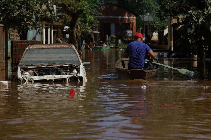 Um homem rema em uma canoa entre as ruas alagadas do bairro Encantado, no Rio Grande do Sul. Fortes chuvas causam enchentes no Rio Grande do Sul desde o fim de semana        -  (crédito: Silvio Avila/ AFP)