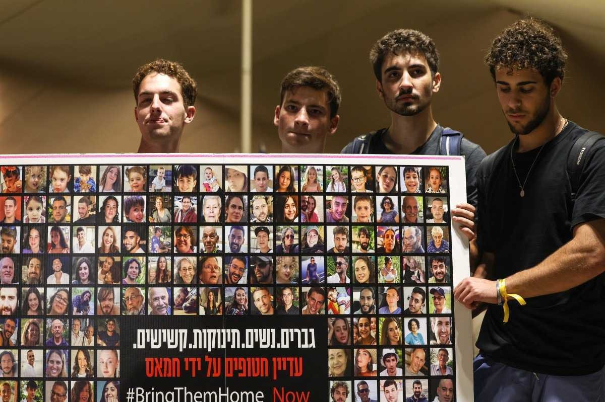 Parentes, amigos e apoiadores de reféns israelenses mantidos em Gaza desde o ataque de 7 de outubro por militantes do Hamas no sul de Israel, seguram cartazes e imagens daqueles tirados durante um protesto pela sua libertação em Tel Aviv em 22 de novembro de 2023.